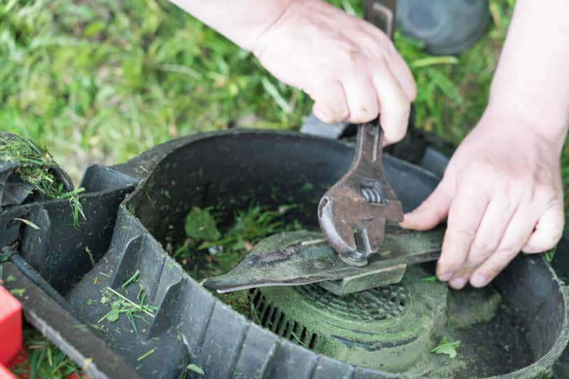 Man balancing lawn mower blade in his lawn