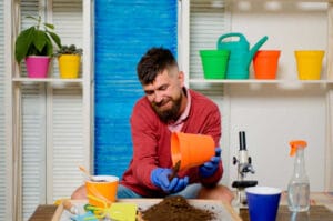 Happy man is played with plants. Soil for house plants.