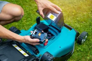 Gardener putting battery into electric cordless lawn mower