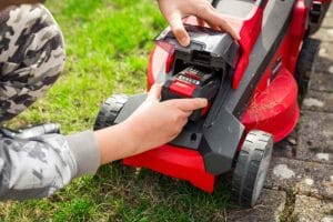 Gardener changes rechargeable battery in riding lawn mower